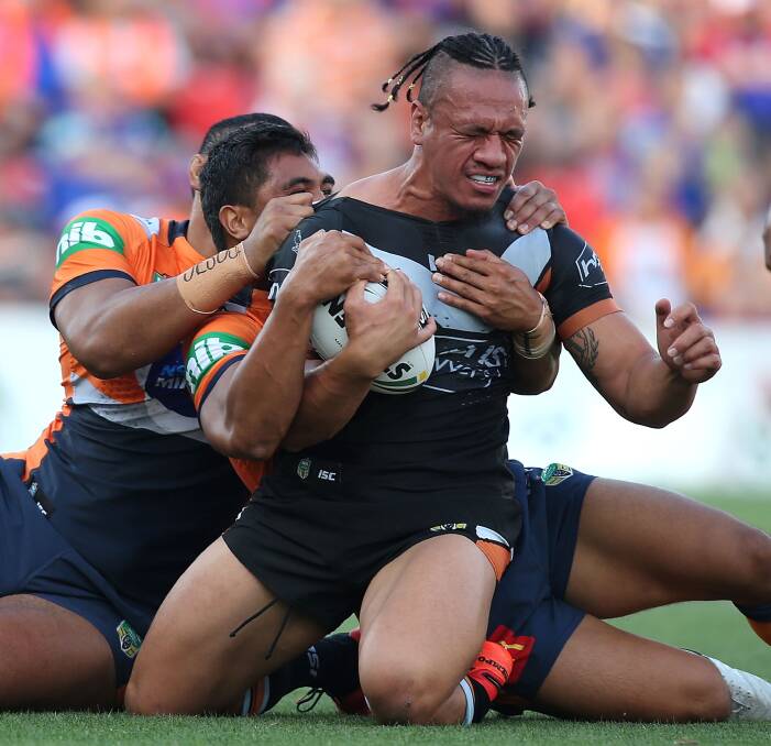 ARM WRESTLE: Newcastle defenders halt the progress Wests Tigers lock Sauaso Sue at Hunter Stadium on Sunday. Picture: Getty Images