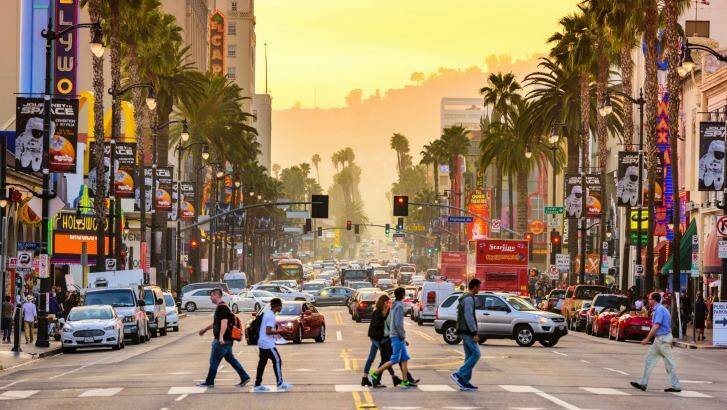 Pedestrians cross traffic on Hollywood Boulevard at dusk, Los Angeles. Photo: iStock