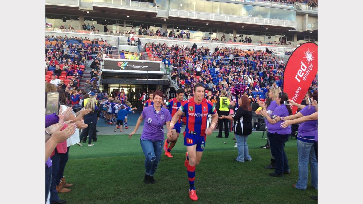Lindy Hunt running on the field with Kurt Gidley leading the rest of the Newcastle Knights
