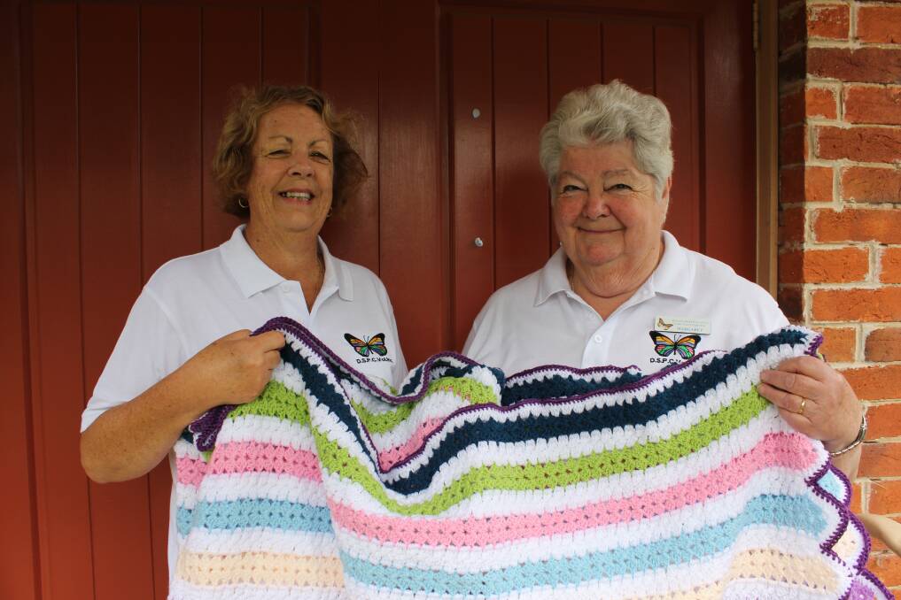 COMMUNITY: Dungog Shire Palliative Care Volunteers Inc members Lyn Moseley and Margaret Jones with the celebatory crocheted rug which is the major prize. Photo; Michelle Mexon