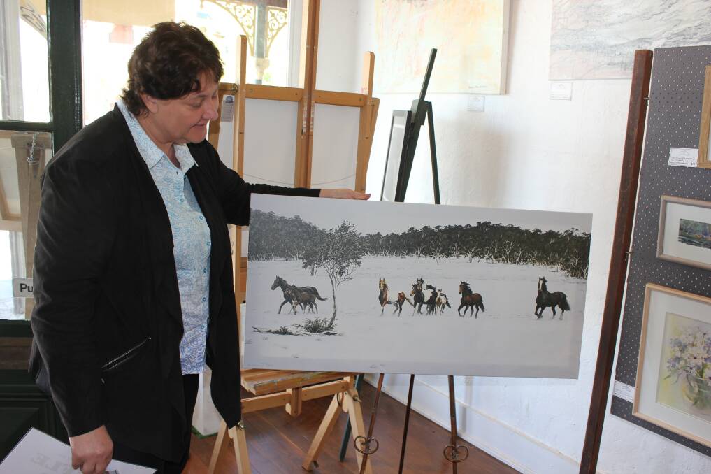 PRIZE: Dungog Arts Society member Simone Turner Ryan with a print of her popular artwork Brumbies Of the Barrington which is the raffle prize this year.