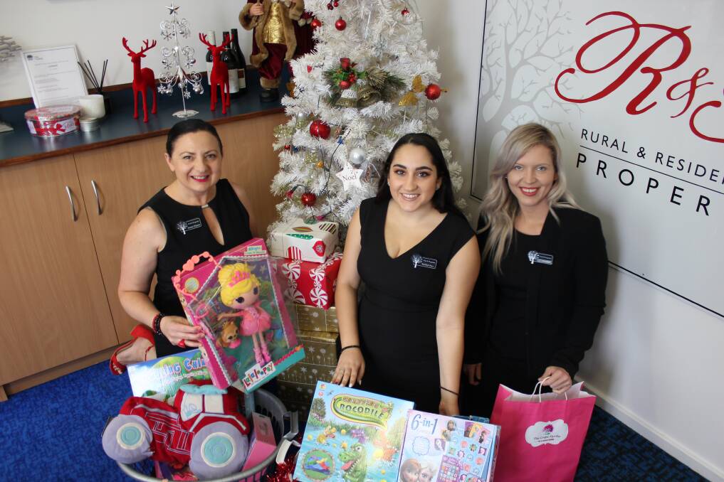 GIVING TREE: Principal of R and R Property Denise Haynes with Rachael Pace and Lisa Coburn and some of the gifts already left by generous residents at the Cowper Street office for the Dungog Shire Community Centre.