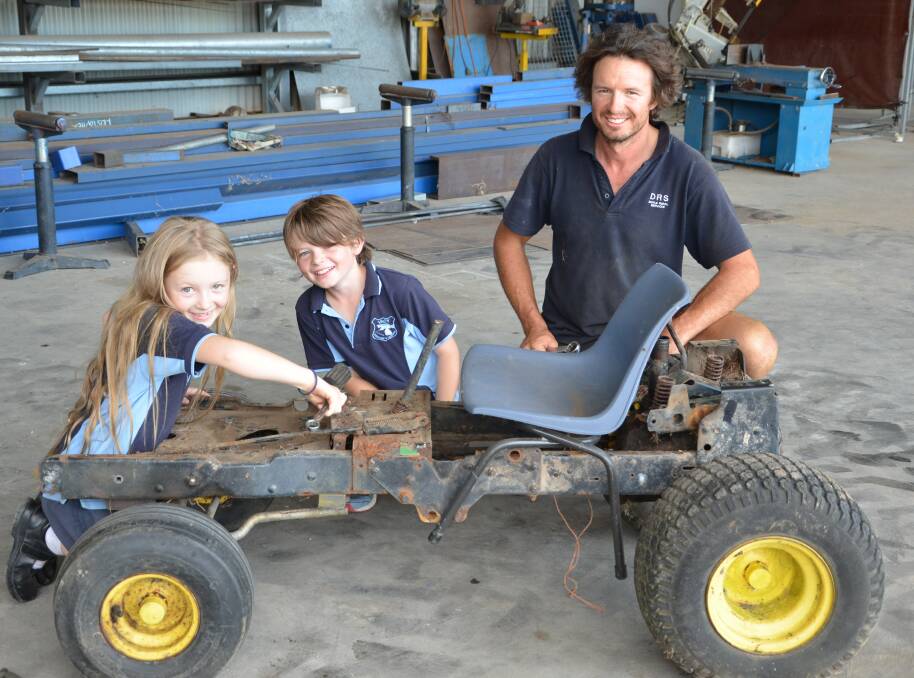 Kris Doyle with son Tom and daaughter Eva working on their billy cart in the lead-up to the Gresford Billy Cart Derby.