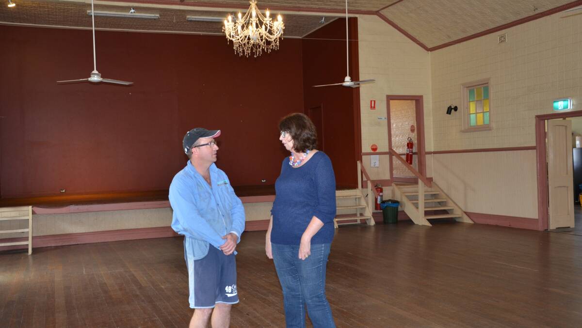 CLASSY LIGHTING: Electrician Dave Watson and Clarence Town School of Arts committee president Colleen Duffy with the new chandeliers recently installed.