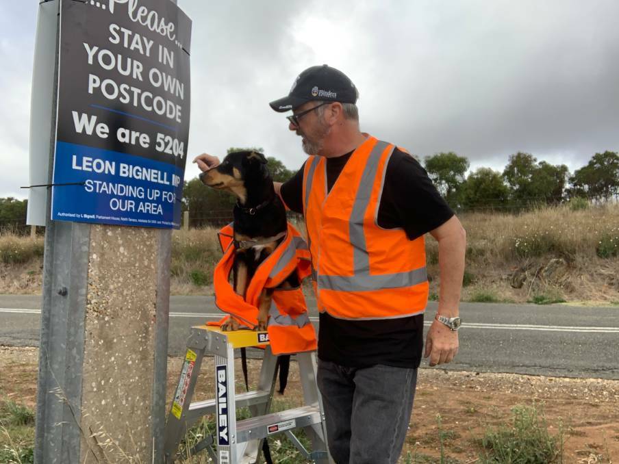 STAY HOME: State Member for Mawson, Leon Bignell and his Kangaroo Island kelpie puppy Dusty back in March 2020 put up coronavirus signs urging people to stay in their own postcode and not visit. 