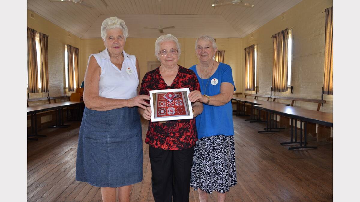 Gresford Red Cross members Margot Capp, Phyllis Draper and Alma Landers with a photo of the hand-made quilt.